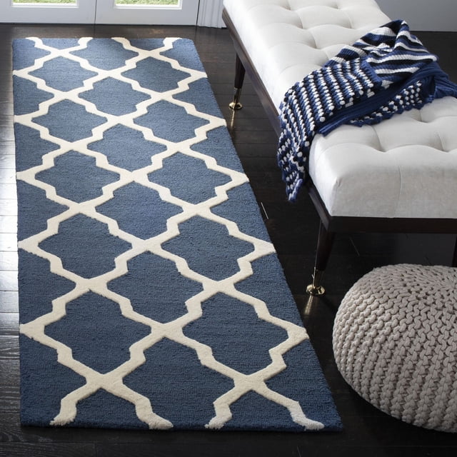 Safavieh Cambridge Liam Tapis Géométrique Bleu avec Motif de Treillis Géométrique Blanc, Laine Tuftée à la Main avec texture de Poil Pelucheux Coupé et Bouclé, sur Plancher de Bois Franc Foncé à Côté d'Un Banc Tufté Blanc avec Jeté en Tricot Bleu et Blanc et pouf Tricoté beige, Convient pour Ajouter un style Américain Moderne à la Maison Ou au Bureau.