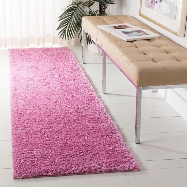SAFAVIEH August Carlene Tapis Shag Uni en Peluche Rose Vif avec Fil de Polypropylène Épais, Rectangulaire sur Plancher de Bois Franc Blanc à Côté d'Un Banc Capitonné beige avec Pattes Chromées dans une Pièce Lumineuse avec des Rideaux Transparents et une Plante Verte, Idéal pour Ajouter Douceur et Couleur aux Entrées Ou aux Couloirs.