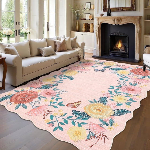 Garvee 5'x7' Floral Area Rug in pink displayed in a living room setting. The rug showcases a boho-inspired design with colorful floral motifs and butterflies, complemented by a scalloped edge. Made of polyester with a non-slip thermoplastic rubber backing, it has a low pile height of 0.3 inches. This stain-resistant and washable rug is ideal for high-traffic indoor areas like living rooms, bedrooms, and dining rooms, offering durability and easy maintenance.