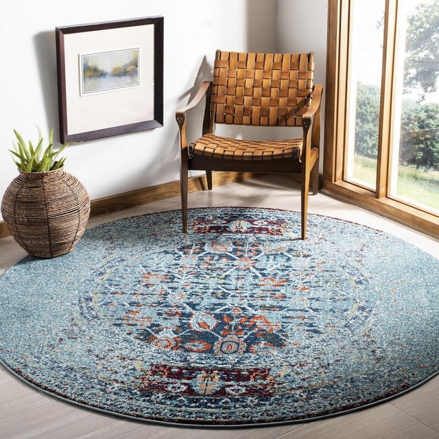 Safavieh Monaco Annabelle Vintage Area Rug, round with a power-loomed polypropylene pile in blue and red distressed Persian design, displayed in a bright corner with a woven leather strap armchair, wicker planter, and framed artwork, ideal for adding bohemian flair to home interiors.