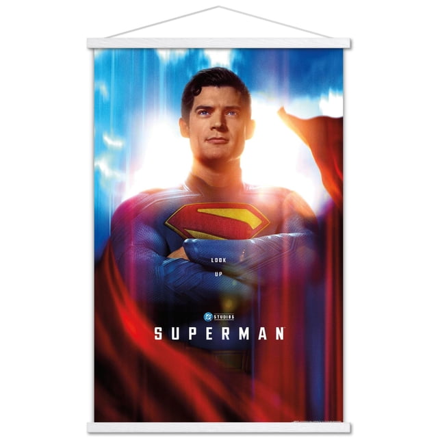 DC Studios Superman (2025) - Affiche Murale Gros Plan d'Une Feuille Montrant une Vue Centrée de Superman avec les Bras Croisés Portant un Complet Texturé Bleu avec un Emblème « s » Rouge et Jaune, Adossé à un Ciel Lumineux avec des Nuages et une cape Rouge Fluide, Imprimée sur Papier d'Art photo Lustré et Encadrée avec des rails Magnétiques en Bois Blancs, Mesurant 22,375 par 34 Pouces, Convient à la Décoration Murale de la Maison Ou du Bureau.