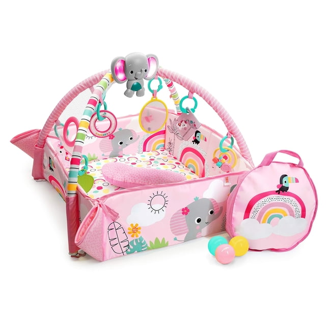 Bright Starts 5-In-1 Your Way Ball Play Activity Gym & Ball Pit in Rainbow Tropics design. A versatile baby activity gym featuring a colourful playmat with adjustable walls, mesh canopy, and arches adorned with hanging toys including a musical elephant, unicorn crinkle toy, mirror, flashcards, leaf toy, and bead rattle. Includes 40 balls with a rainbow-themed carrying case. Dimensions are 30 x 44.5 x 21 inches.