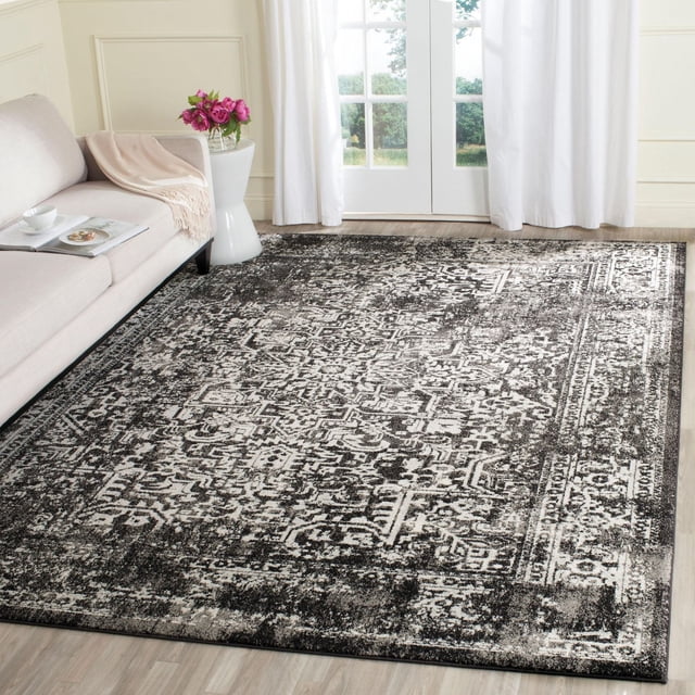 Safavieh Evoke Tapis Traditionnel Trena Présentant un Motif Géométrique Noir et Blanc Vieilli avec une texture de Frise Douce, Posé sur un Plancher de Bois Franc Clair dans un Salon Lumineux avec un sofa beige, des Rideaux Blancs et une table d'Appoint avec des Fleurs Roses, Idéal pour Rehausser le style et le Confort dans la Déco de la Maison.