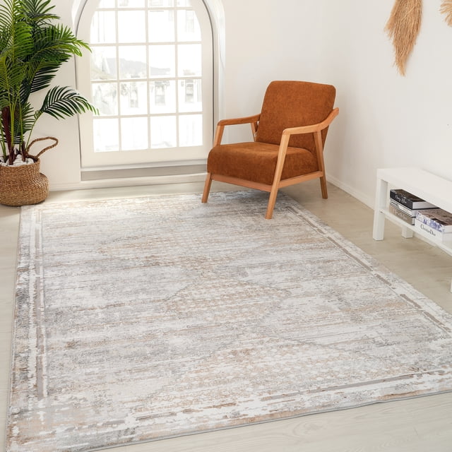 Rug Branch Atlas Vintage Indoor Area Rug in brown grey with a boho pattern, shown in a bright room with a rust-coloured armchair with wooden arms, a large arched window, a woven basket planter with green foliage, and a white side table holding books, suitable for living room or bedroom settings.