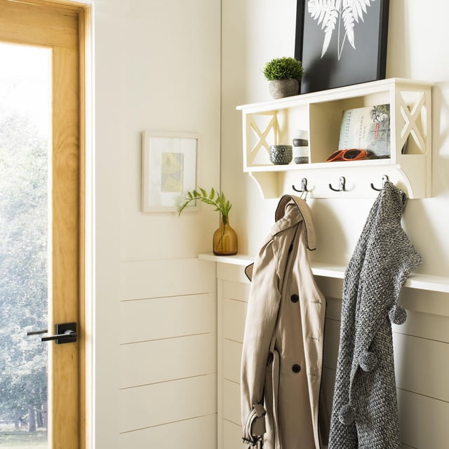 Safavieh Freya Étagère Murale de Rangement Suspendue en Crème avec Trois Crochets Doubles Tenant un Trench-Coat beige et une Foulard Tricotée Grise avec Pompons, avec Compartiments Ouverts avec Articles Décoratifs au-Dessus de Lambris Blancs Près d'Une Porte en Bois dans une Entrée Lumineuse, Convient pour Organiser Manteaux et Accessoires.
