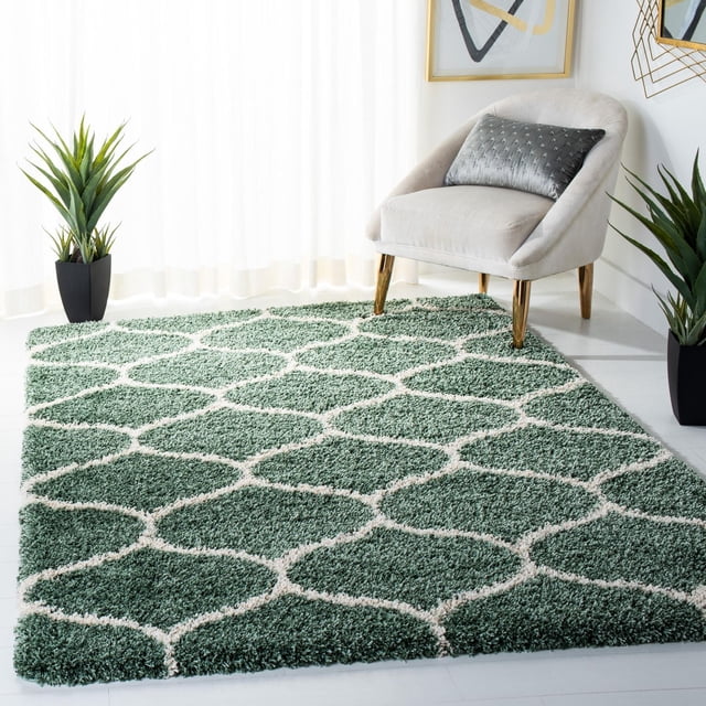 Safavieh Hudson Tapis Shag Géométrique Arline avec Poil Shag Peluche Vert et Motif de Carreaux en Forme d'Oignon Blanc, Exposé sur un Plancher Blanc à Côté d'Une Chaise d'Appoint beige avec Pattes Dorées et Deux Plantes Vertes en Pot, Convient pour Rehausser la texture dans les Salons Modernes.