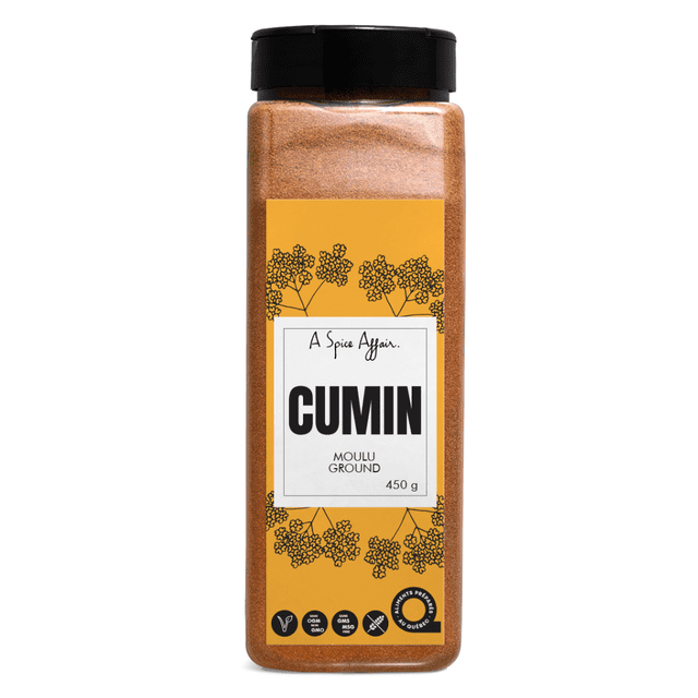 Cumin Ground 450g (15.9 oz) A Spice Affair Large Shaker. The shaker has a clear container filled with finely ground cumin, a spice known for its nutty and slightly peppery taste. It features a black twist-off lid and a yellow label with floral designs, emphasizing its non-GMO, vegan, and gluten-free qualities.