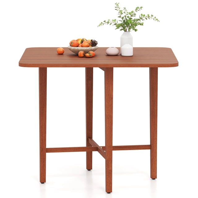 Costway Foldable Dining Table for 2-4 People in a warm walnut finish, featuring a square tabletop with dual drop leaves and sturdy rubber wood legs. The table includes an X-shaped frame for enhanced stability and adjustable foot pads for balance on uneven surfaces. Shown fully extended with decorative items, it is suitable for dining, writing, or use as a console table. Dimensions: 36 x 36 x 29.5 inches when fully extended.