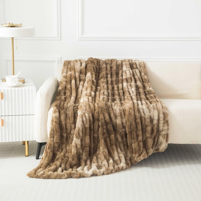 Hometrends Couverture Jetée Réversible en Fausse Fourrure dans des Tons Bruns Chauds, Drapée sur un sofa beige. la Couverture de 50 par 60 Pouces Présente une texture en Fausse Fourrure Côtelée à Poils Longs, Offrant un accent Douillet pour la Déco de la Maison et la Chaleur pour Se Détendre Ou Lire.