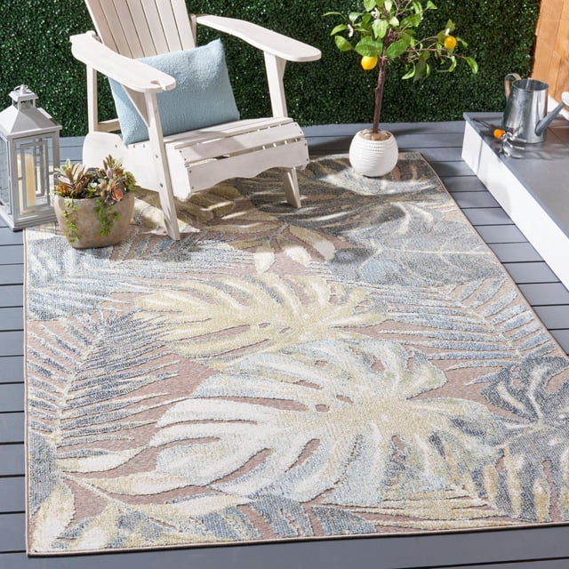 SAFAVIEH Sarasota Alexa Floral Indoor/Outdoor Area Rug with tropical leaf patterns in beige, blue, and cream tones, displayed on a grey deck with a white Adirondack chair, blue cushion, potted plants, and a lantern, ideal for enhancing outdoor or indoor living spaces.