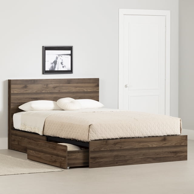 South Shore Musano Queen 2-Drawer Complete Bed in natural walnut finish with two large storage drawers on wheels, one drawer open showing storage space, featuring a clean-lined headboard and beige quilted bedding with white pillows, set in a minimalist room with white walls, a black and white framed photo, and a white door, ideal for maximizing bedroom storage without a boxspring.