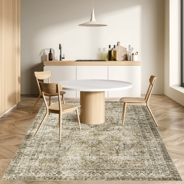 HOMERRY Washable 9' x 12' Area Rug for Living Room in taupe, featuring a traditional boho-inspired floral design with distressed textures. The rug is displayed in a modern dining area with light wood furniture and a minimalist kitchen backdrop. Made with non-slip TPR backing, it is suitable for high-traffic areas and safe for kids and pets. Crafted from faux wool fibers, it is machine washable, quick-drying, and wrinkle-resistant, ideal for versatile use on tile, wood, or marble floors.