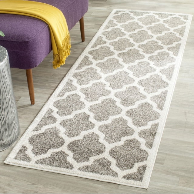 Safavieh Amherst Tapis Géométrique Rodick pour Aire avec Motif Treillis Géométrique beige et Blanc Cassé et texture Polypropylène à Poil Coupé, Placé sur un Plancher de Bois Clair à Côté d'Un Banc Violet avec des Pattes en Bois et un Jeté Jaune, Convient à une Utilisation durable Intérieure-Extérieure dans les Zones à Fort Passage.