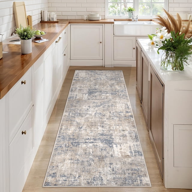 BERTHMEER 2'x8' washable abstract runner rug in blue, placed in a bright kitchen with wooden countertops and white cabinets. The low-pile rug features a modern abstract design with blue and neutral tones, made of polyester and thermoplastic rubber for durability and non-slip functionality. Suitable for hallways, kitchens, and entryways.