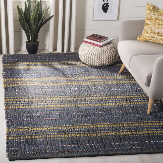 Safavieh Natural Fiber Ombre Striped Area Rug featuring woven sisal texture with horizontal stripes in dark blue, yellow, and red accents, displayed in a living room under a beige sofa and cream knitted pouf, near a snake plant and light curtains, ideal for coastal or casual interiors.