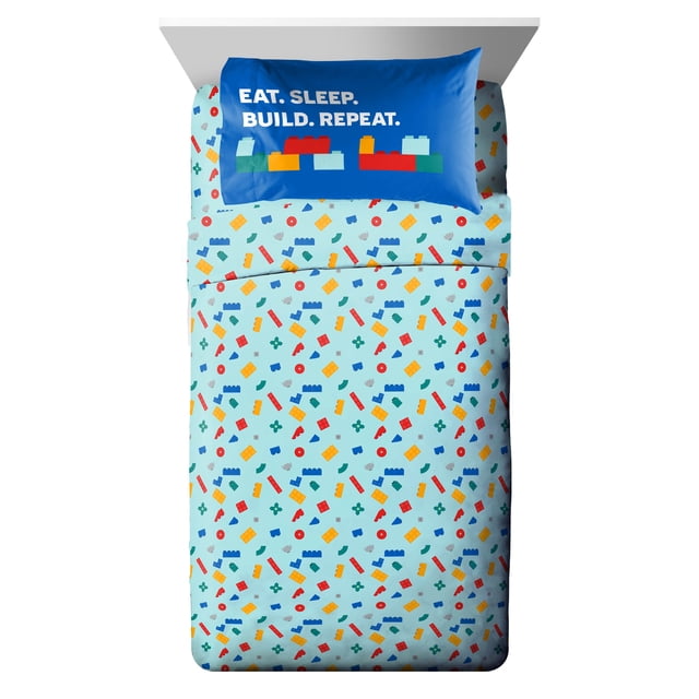 Lego Twin Sheet Set with light blue fitted and flat sheets printed with colorful LEGO brick patterns in red, yellow, blue, and green. The blue pillowcase shows white text 'EAT. SLEEP. BUILD. REPEAT.' above LEGO brick graphics. Made from soft 100% polyester, this kids bedding set is machine washable for easy care.
