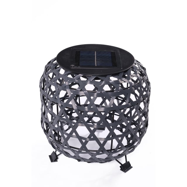 Dura Osier Synt Solar Lantern with a black synthetic osier open-weave round frame, flat solar panel on top, and three small legs, designed for outdoor lighting on patios, balconies, or courtyards, also suitable for indoor ambient decor after charging.