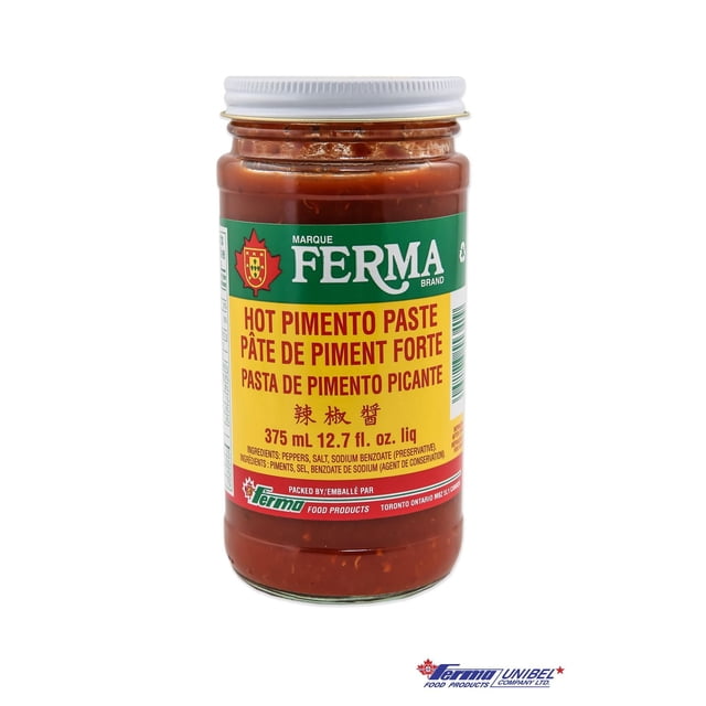 Ferma Piment Chaud Paste dans un Pot en Verre Transparent avec Couvercle Blanc à Vis, Présentant une Étiquette Verte et Jaune avec Texte Rouge, Contenant 375 ml (12.7 fl. oz) de condiment Épicé Idéal pour Rehausser la Saveur de la Viande, de la Volaille, du Poisson, des Fruits de Mer et des sauces, Souvent Utilisé comme un Incontournable Polyvalent du Garde-Manger.