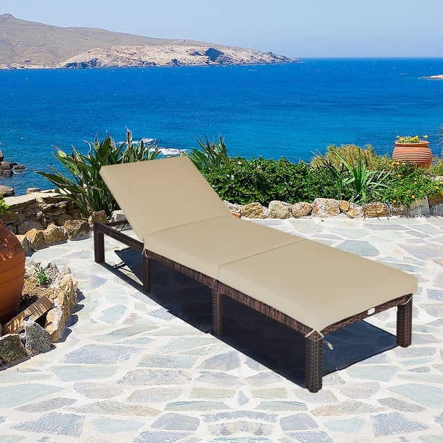 Gymax Chaise Longue de Patio en Rotin Fauteuil Inclinable d'Extérieur avec 6 positions Réglables et Coussin beige, Conçu avec un Cadre en Rotin Brun durable. Idéal pour une Utilisation Extérieure comme Mobilier de Patio Ou Chaise Longue d'Extérieur, Montré sur un Patio en Pierre avec une Vue sur le Bord de Mer.