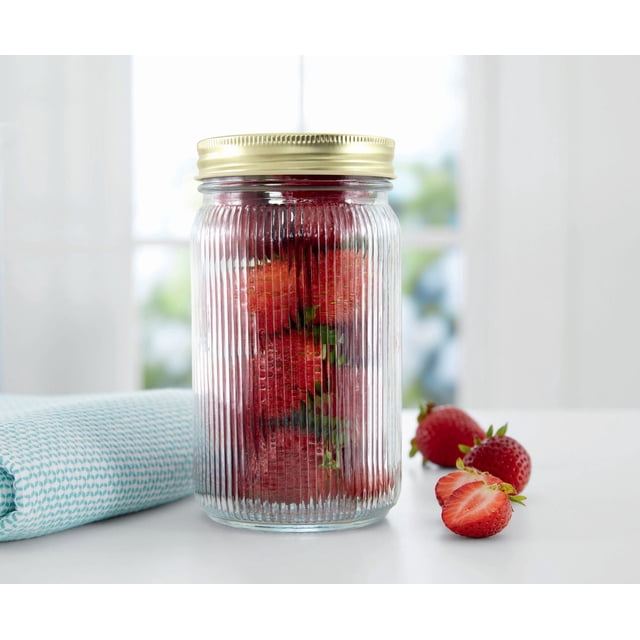 Pot en Verre Nervuré MS 1L OS en Verre Nervuré Transparent Sans BPA avec Couvercle Hermétique Doré, Rempli de Fraises Fraîches, Placé sur une surface Blanche à Côté d'Un Tissu Plié à Motif Bleu et de Fraises en Vrac, Idéal pour le Rangement des Aliments et l'Organisation du Garde-Manger.