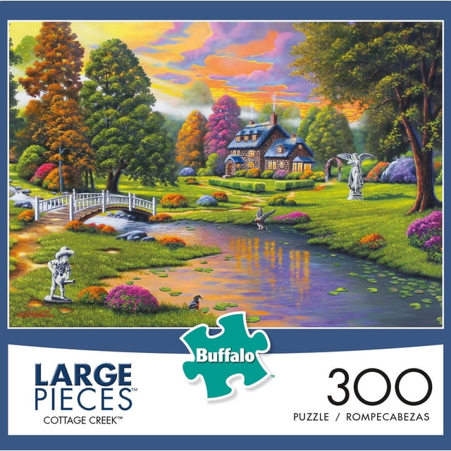 Buffalo Games - Cottage Creek - 300 Piece Jigsaw Puzzle depicting a stone cottage with glowing windows in a vibrant autumn setting, a white wooden bridge over a lily pad-covered pond, garden statues, and a colorful sunset sky, suitable for fans of large-piece jigsaw puzzles.