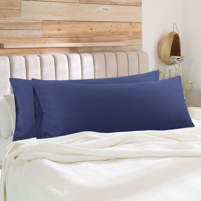 PiccoCasa 2Pcs Body Pillowcases Microfiber Pillow Covers in navy blue, displayed on a bed with a beige upholstered headboard and wooden accent wall. The pillowcases, made of 1800 series brushed microfiber, measure 20 x 54 inches and feature an envelope closure for easy use. Suitable for bedrooms, guestrooms, or sofas, these machine-washable pillowcases are soft, breathable, and wrinkle-resistant.