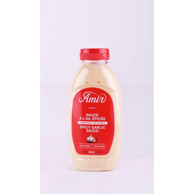 Amir-SAUCE Épicée dans une Bouteille Compressible en Plastique Transparent avec un Bouchon Rouge et une Étiquette Lisant « Amir SAUCE à l'Ail Épicé » en Anglais et en Français. la SAUCE beige Crémeuse avec des Taches d'Épices Visibles Est Fraîche et Naturelle, Idéale pour les Sautés, les marinades et la Cuisson, avec un Poids net de 350 ml.