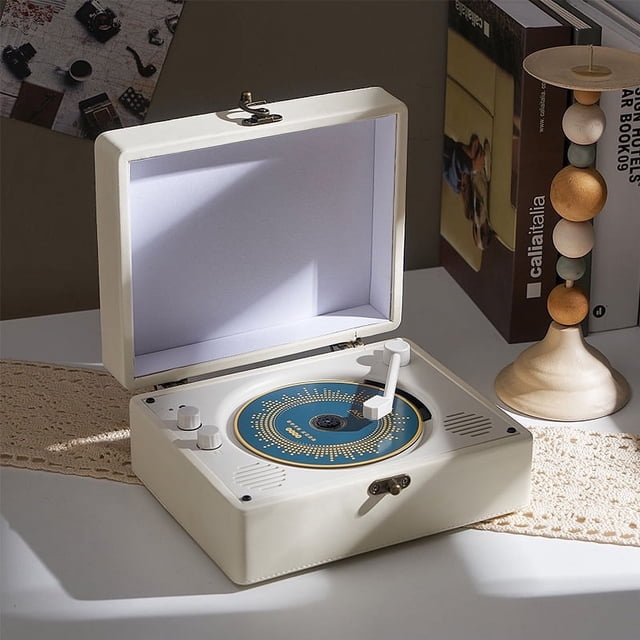POINTERTECK CD Player avec Bluetooth au design Rétro dans une Boîte en Bois de Style Valise en Cuir. le Bureau CD Player Comprend des Haut-Parleurs Doubles Hi-Fi Intégrés, Connectivité Bluetooth 5.0, et Prend en Charge les formats CD/CD-R/CD-RW/MP3. Il Fonctionne Aussi comme radio FM, Lecteur de Clé USB et mini Haut-Parleur pour la Maison. l'Image Montre le CD Player Ouvert sur une table, avec un Couvercle Anti-Poussière et un Cadre Décoratif Incluant des Livres et un Chandelier en Bois.