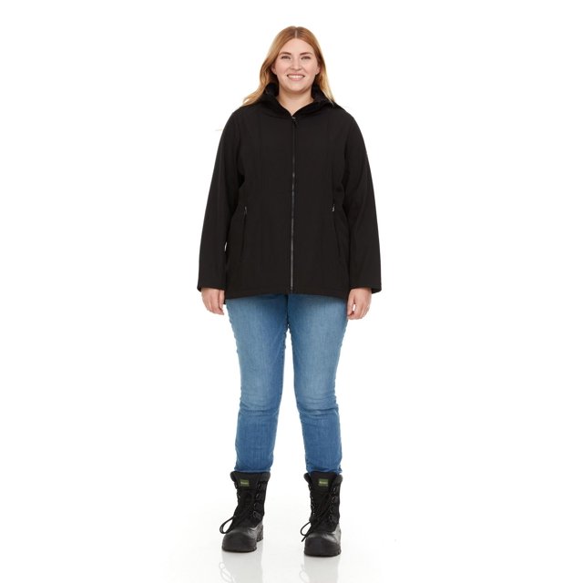 Swiss Tech Veste Coquille Souple à Capuche pour Femme Grande Taille en Noir, Vue de devant d'Un Modèle Portant un Jean Bleu Pâle et des Bottes à Lacets Noires, avec Fermeture Éclair Intégrale, Poches pour les Mains Zippées, et Capuche Amovible avec Cordon de Serrage Ajustable, Fabriquée en Coquille Souple Extensible Résistante à l'Eau Liée à une Microfibre pour la Chaleur et la protection contre les Intempéries.