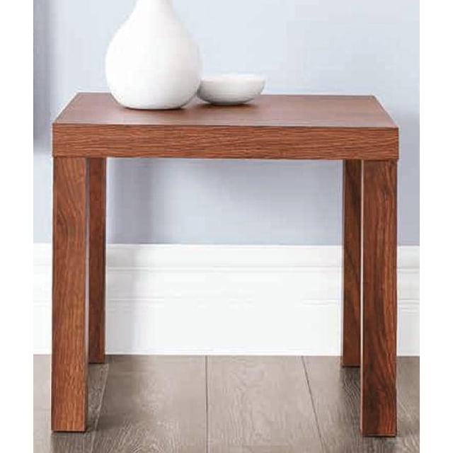 Hometrends End Table in canyon walnut finish with a simple modern square design, four straight legs, and a flat top, positioned on a wood floor against a pale blue wall, holding a white vase and small bowl, suitable for living room use or as a compact side table.