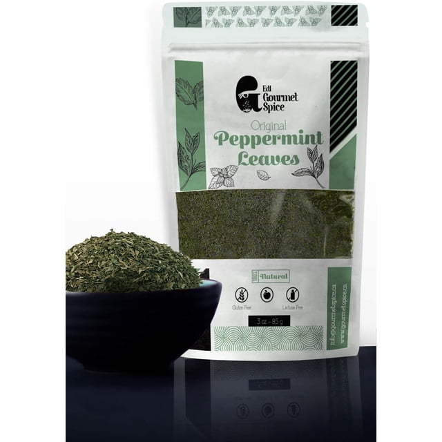 Edi Gourmet Spice Dried Mint Leaves - 85g / 3 oz, shown in a resealable craft paper bag with green and white design, featuring the label 'Original Peppermint Leaves' and icons indicating gluten-free and lactose-free. A black bowl filled with dried and crushed mint leaves is placed in the foreground.