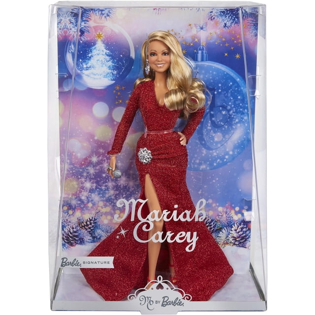 Mariah Carey Barbie Doll, Holiday Celebration Collectible wearing a glittery red long-sleeve gown with ruched hip overlay and thigh-high slit, adorned with a silver brooch, red heels, and holding a silver microphone, displayed in a clear box with a festive winter backdrop featuring snow-covered pine branches and blue ornaments.