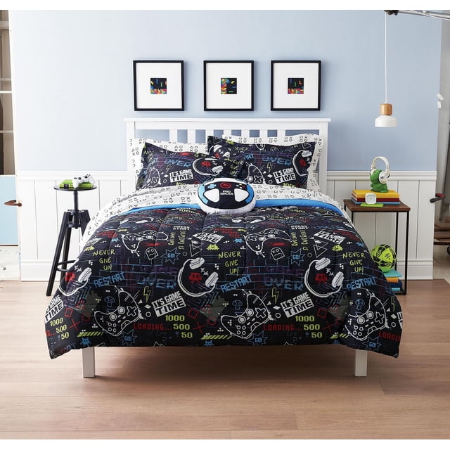 Mainstays Kids Gamer Glitch Ensemble de Literie Tout-en-un avec Couette en Microfibre Bleu Marine, Présentant des Graphiques Colorés de console de Jeu Vidéo et des phrases Motivationnelles comme « Ne Jamais Abandonner » et « l'Heure du Jeu ». l'Ensemble Comprend des Taies d'Oreiller Coordonnées, un Coussin Rond avec Manette de Jeu, et un Ensemble de Draps Imprimés Blanc et Noir sur un Cadre de Lit à Lattes Blanc dans une Chambre d'Enfant Bleu Pâle avec art pixel au-Dessus de la Tête de Lit.