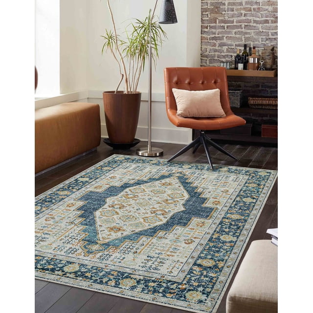 ECARPET Kinsley Traditional Area Rug with copper and navy geometric medallion patterns on a light background, placed on dark hardwood flooring in a living room with a brown leather swivel chair, beige cushion, tall potted plant, and modern floor lamp, suitable for durable, stain-resistant use in busy family rooms.