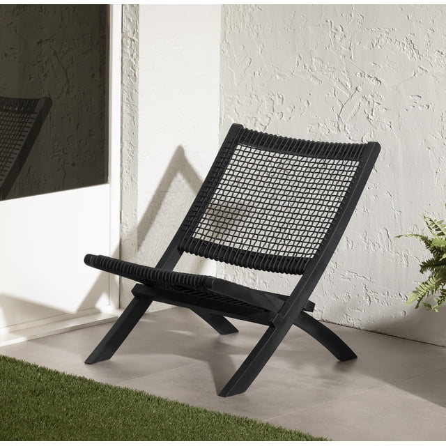 South Shore Agave Wood and Woven Rope Lounge Chair in black with a teak wood frame and woven polyester rope seat and backrest, placed on a tiled outdoor patio near a white textured wall and glass door, ideal for durable, low-maintenance outdoor seating with a bohemian style.