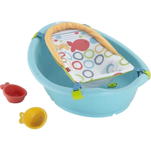 Fisher-Price Rinse 'n Grow Tub in light blue with a multicolour mesh sling featuring fish and circle patterns, secured by yellow and blue straps, with red and yellow goldfish strainer cups, designed for newborn to toddler bath stages with built-in drain plug.