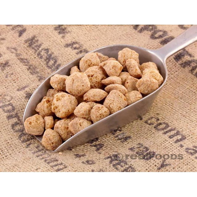 TVP Chunks Soya Textured Vegetable Protein 22 lbs displayed in a metal scoop on a burlap surface. The chunks have a light brown, textured appearance, ideal for adding plant-based protein to various dishes such as casseroles, meatless burgers, and baked goods. Packaged in a bulk 22-lb size, suitable for vegetarian and vegan cooking.