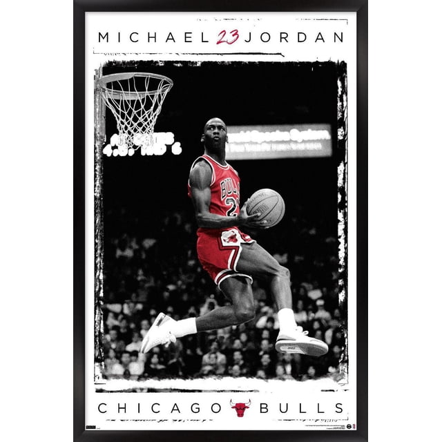 Michael Jordan - Dunk Wall Poster, 14.725" x 22.375" framed showing Michael Jordan in a red Chicago Bulls uniform mid-air performing a basketball dunk near the hoop with a black and white crowd background, featuring 'MICHAEL 23 JORDAN' text at the top and 'CHICAGO BULLS' with the team logo at the bottom, ideal for sports-themed room decor.