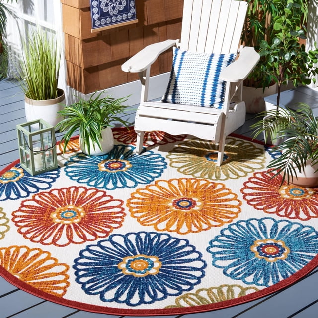 SAFAVIEH Cabana Aria Floral Outdoor Area Rug with a round shape and large floral patterns in blue, orange, red, and green on a cream background, placed on a gray deck with a white Adirondack chair holding a blue and white cushion, surrounded by green potted plants and a green lantern, ideal for outdoor patios or porches.