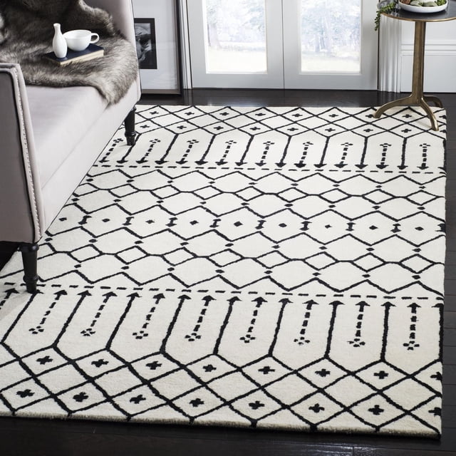 Safavieh Himalaya Darin Geometric Area Rug featuring black and white diamond and linear patterns on 100% hand-loomed wool, placed on dark hardwood flooring beside a grey sofa and round gold side table, ideal for modern living room decor and durable accent use.