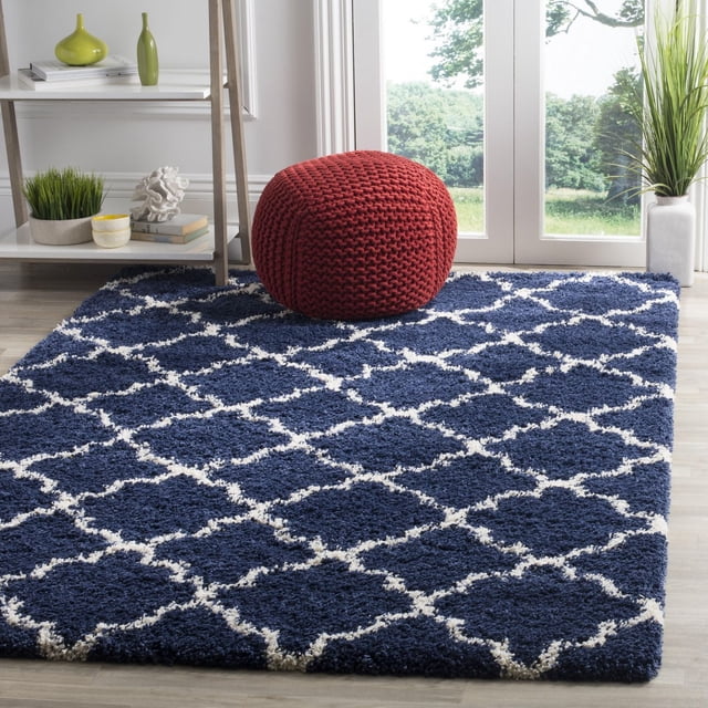 Safavieh Hudson Tapis Shag Géométrique Jaye Bleu Marine avec Motif de Carreaux Blancs et Épais Velours Shag sur Plancher de Bois Clair, Style avec un pouf Tricoté Rouge et des Plantes Vertes Près des Portes en Verre, Convient pour Ajouter de la texture aux Espaces de Vie Modernes.