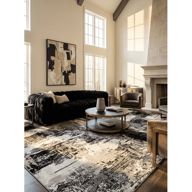 Rug Branch Atlas Classic Indoor Area Rug in grey beige with a modern abstract pattern, placed in a sunlit living room featuring a black plush sofa, round wooden coffee table with books and a vase, beige armchairs, a stone fireplace, and large windows with natural light. This durable polyester rug is ideal for high-traffic areas and enhances living room decor.