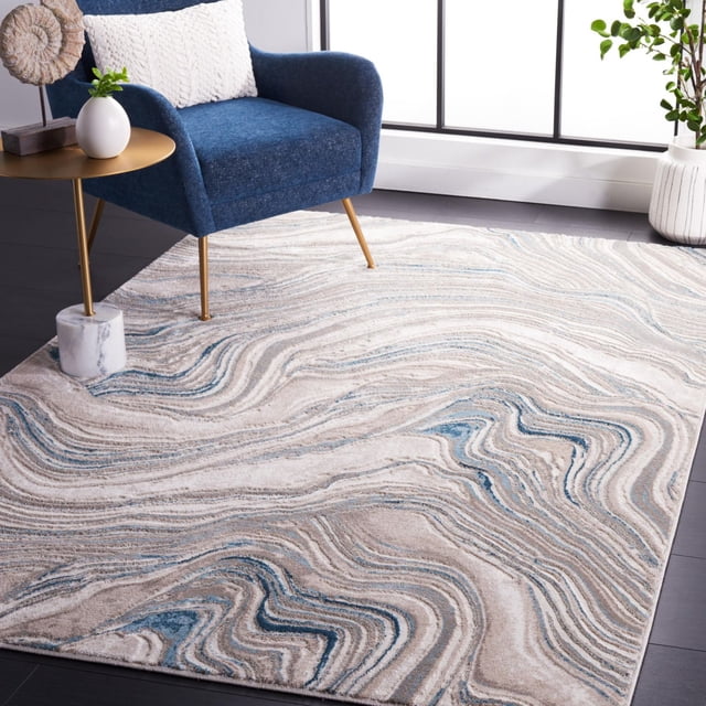 SAFAVIEH Meadow Joey Contemporary Area Rug with an abstract swirling pattern in beige, cream, and blue tones, made from a durable polyester and polypropylene blend, displayed on dark hardwood flooring under a blue upholstered armchair with gold legs, next to a gold round side table with a white vase and decorative object, in a bright room with large windows and a potted plant. This versatile accent rug is ideal for living rooms and offices.