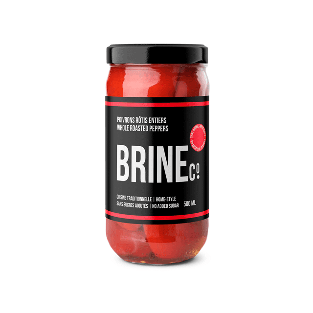 Brine Co Whole Roasted Peppers 500ML Jar with vibrant red whole roasted peppers inside a clear glass jar. The black label highlights no added sugar, artisanal home-style recipe, and product of Greece. Ideal as a condiment or topping for pantry food dishes. The jar has a black lid and is shown on a white background.