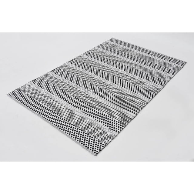 Vista Area Rug shown in a 3/4 angled view with a low pile height, featuring black and white geometric diamond stripes in a flat weave, ideal as a kitchen mat or entryway rug for high-traffic home areas.