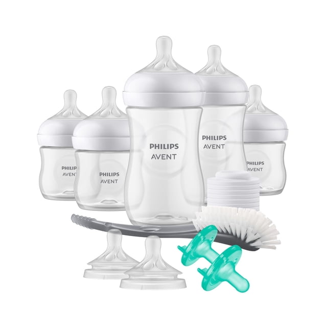 Philips Avent Natural Baby Bottle Newborn Baby Gift Set, SCD838/02 with five clear polypropylene bottles featuring white breast-shaped nipples for natural feeding, two extra nipples with different flow rates, a curved bottle brush with white bristles and molded tip, seven sealing discs for storage, and two green Soothie pacifiers for newborns, arranged on a white background.