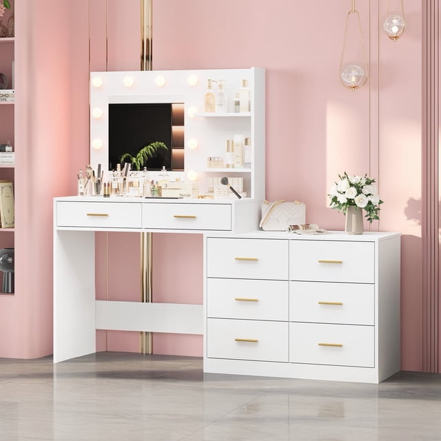 Yiwa Large Vanity Table with Lighted Mirror, featuring 8 storage drawers, 2-tier shelves, and 3 lighting modes, shown in a modern bedroom setting. The white MDF construction includes gold-tone handles and a spacious tabletop for organizing cosmetics and beauty tools. The lighted mirror is framed by 10 bulbs with adjustable brightness and three color modes: natural, warm, and cool. The vanity is paired with a matching side cabinet for additional storage, set against a pink wall with decorative accents.