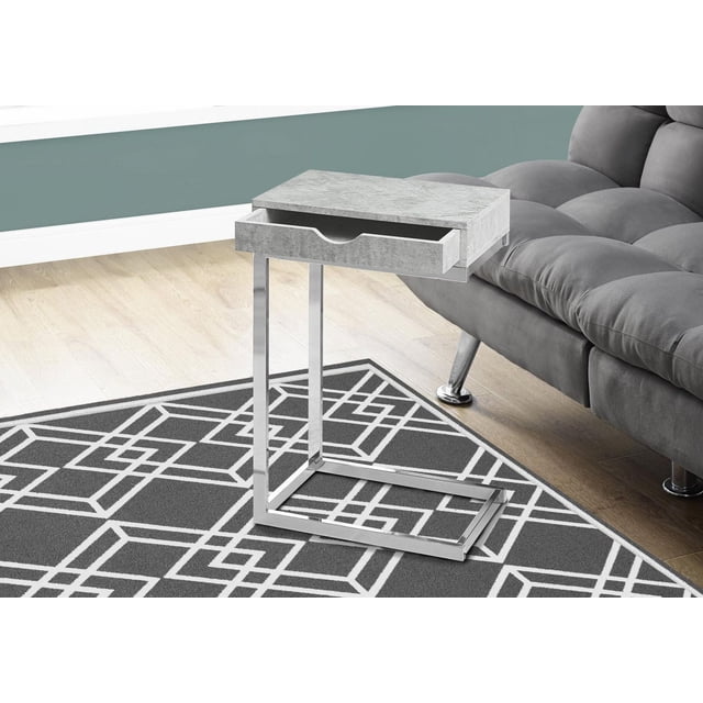 Monarch Specialties Accent Table, C-shaped end and side table with grey laminate top featuring a concrete finish and a storage drawer, supported by a chrome metal base, positioned next to a grey tufted sofa on a geometric patterned rug, ideal for holding snacks or small living room items.