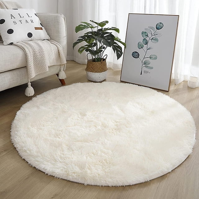 Soft White Round Area Rug for Bedroom Modern Fluffy Circle Rug for Kids Girls Baby Room Indoor Plush Circular Nursery Rugs (80cm). The rug features a dense, soft texture with a non-slip latex particle backing for added safety. Displayed in a cozy room setting with a light wood floor, a potted plant, and decorative elements, this rug is ideal for kids' rooms, nurseries, or playrooms.