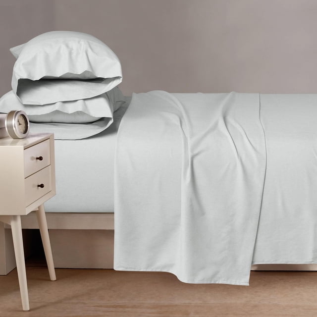Ensemble de Draps en Microfibre Cationique 4 Pcs sur un Lit avec Drap-Housse Gris Pâle, Drap Plat Drapé sur le Côté et Deux Taies d'Oreiller Assorties Empilées à la Tête. Fabriqué à Partir de Microfibre Cationique Brossée à 100 %, Cet Ensemble Respirant et Résistant aux Plis Offre un Confort Toute l'Année. une table de Chevet beige avec Deux Tiroirs et une Horloge Ronde Argentée Se Trouvent à Côté du Lit contre un Mur taupe.